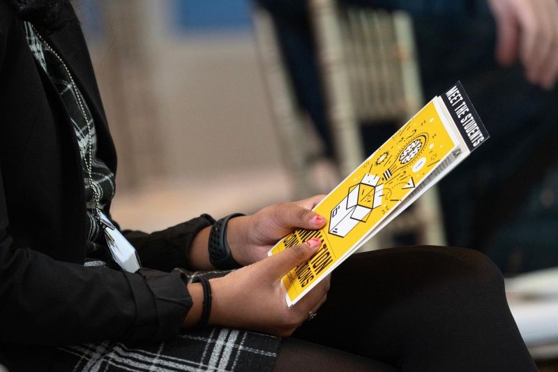 student holding event pamphlet